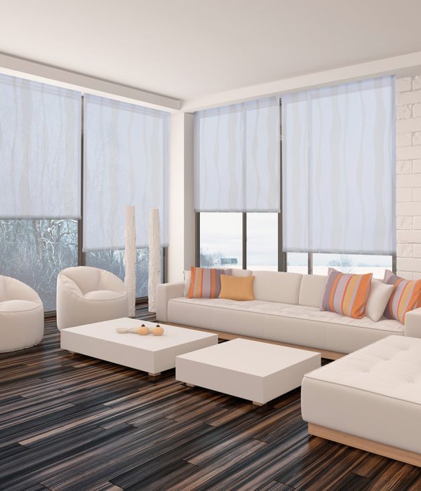 Modern minimalist sitting room interior with a bare wooden parquet floor, contemporary upholstered lounge suite and large view windows with a garden view in a white brick wall
